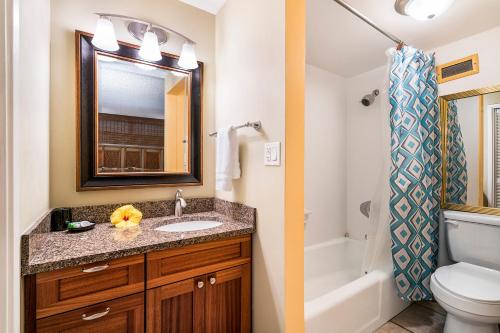 a bathroom with a sink and a toilet and a mirror at Kona Alii 201 in Kailua-Kona