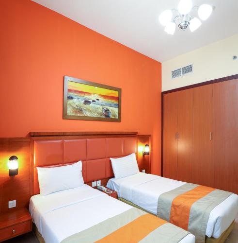 two beds in a hotel room with orange walls at Wescott Plaza Hotel Apartments LLC Formerly West Zone Plaza Hotel Apts in Dubai