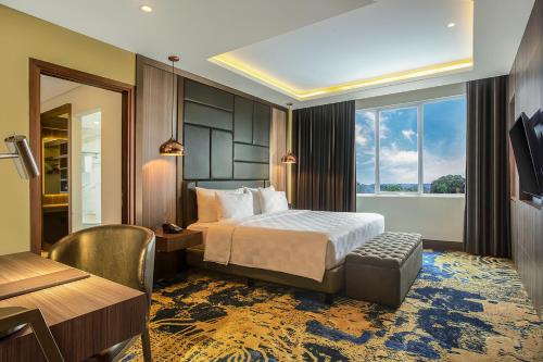 Habitación de hotel con cama, escritorio y ventana en Swiss-Belhotel Cendrawasih, Biak, en Fandoi