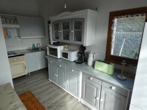 La cuisine est équipée de placards blancs et d'un four micro-ondes blanc. dans l'établissement Maison 30m² avec piscine, terrasse, vélos, proche plage - Notre-Dame-de-Monts - FR-1-540-186, à Notre-Dame-de-Monts