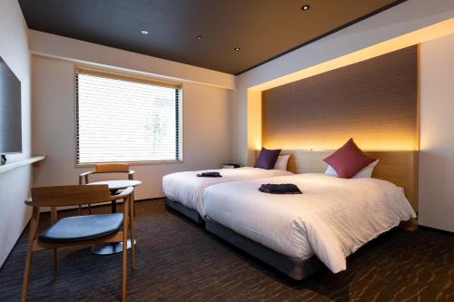 a hotel room with two beds and a desk and a television at The358 SORA in Fukuoka