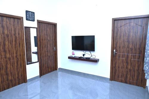 a room with two doors and a tv on a wall at VINNEST in Tiruchchirāppalli