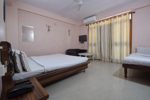 Habitación de hotel con 2 camas y TV en Shreenath JI inn en Udaipur