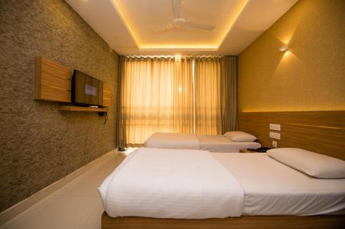 a hotel room with two beds and a television at Hotel Kapilavasthu in Palakkad