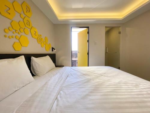 a bedroom with a large white bed with yellow paintings on the wall at Hotel Z zpaze in Bangkok