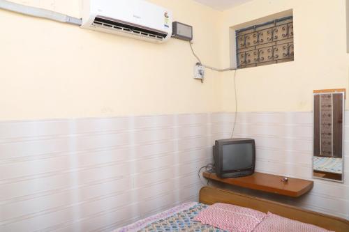 Una habitación con TV y una cama en una habitación en AMMAN LODGE, en Tiruchchirāppalli