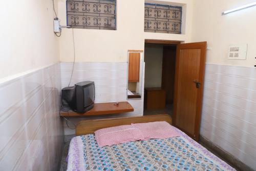 ein Schlafzimmer mit einem Bett und einem TV in einem Zimmer in der Unterkunft AMMAN LODGE in Tiruchchirāppalli