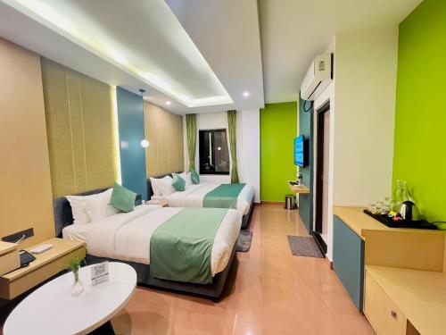two beds in a hotel room with green walls at Hotel Aikawa in Sauraha