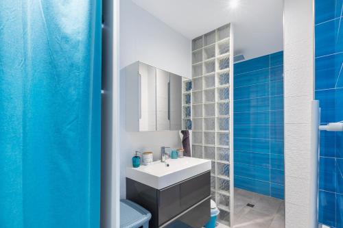 een badkamer met een witte wastafel en blauwe tegels bij O Ciucciarella - Appt climatisé pour 4 in Grosseto-Prugna