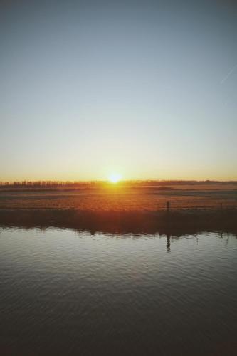 a sunset over a body of water at B&B Herenhuis1919 in Lo-Reninge