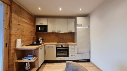a kitchen with white appliances and a wooden wall at Landhotel Lechner Appartements in Kirchberg in Tirol