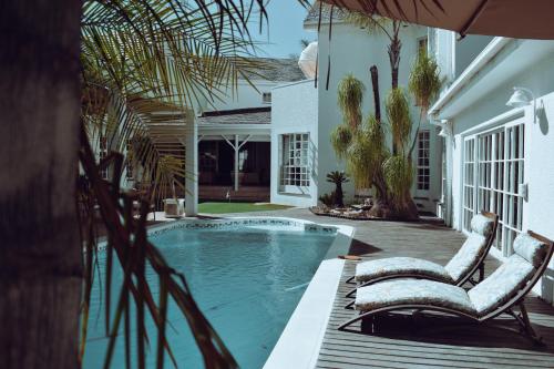una piscina con 2 sillas junto a una casa en Belvedere Boutiqe Hotel en Windhoek