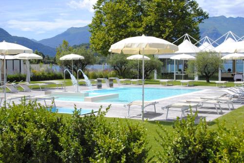 Seven Park Hotel Lake Como - Adults Only في كوليكو: مسبح مع مظلات وكراسي ومسبح