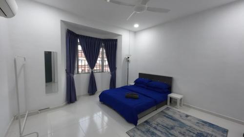 a bedroom with a blue bed and a window at Homestay Sri Pelangi Segamat in Segamat