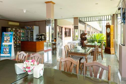 a dining room with a table and chairs and a clock at โรงแรมมณีสังขะ in Sangkha