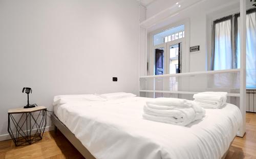 a white bedroom with two beds with towels on them at Ticinese 78 in Milan