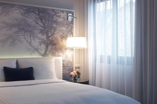 a bedroom with a bed and a window and a lamp at Renaissance Paris Nobel Tour Eiffel Hotel in Paris