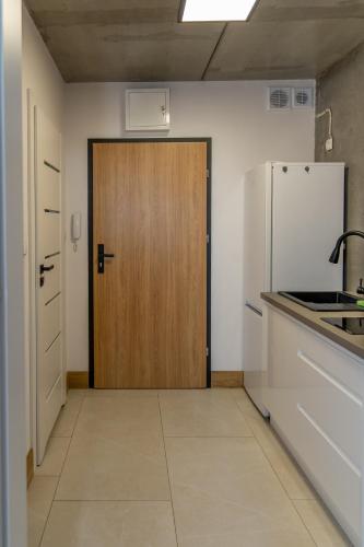 a kitchen with a wooden door and a refrigerator at Apartamenty Przystanek Morska in Gdynia