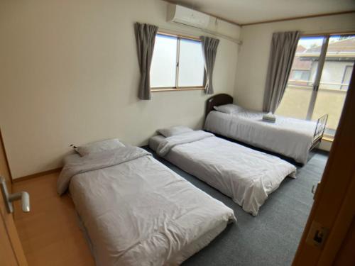 a room with three beds and a window at 3 Bedrooms, 2 Toilets, 3 Car parking in Big Entire house Close to Makuhari Messe, Disneyland, airport and Tokyo for 12 guests in Kuguta