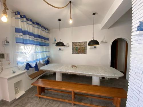 a dining room with a table and a bench at Villa Heraclea sul mare in Trappeto