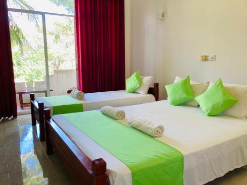 dwa łóżka w pokoju z oknem w obiekcie Sakalya Lake View w mieście Tissamaharama