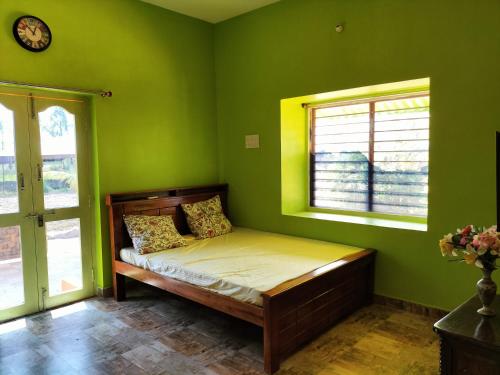 a green bedroom with a bed in a room with windows at CoralbayFarms in Chengalpattu