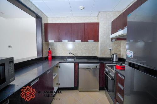 a kitchen with wooden cabinets and stainless steel appliances at Alashrafia Saray 2BR apartment in Sport City in Dubai