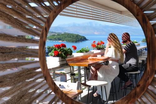 Una novia y un novio sentados en una mesa en un balcón con vistas en Hotel Ajden by Mira Mare en Ksamil