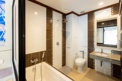 a bathroom with a tub and a toilet and a sink at โรงแรมมณีสังขะ in Sangkha