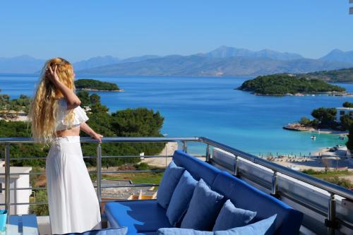 a woman standing on a balcony overlooking a body of water at Hotel Ajden by Mira Mare in Ksamil