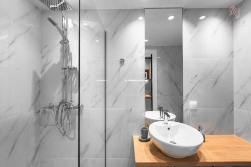 La salle de bains blanche est pourvue d'un lavabo et d'une douche. dans l'établissement Big Apple APRTS, Nilie Hospitality MGMT, à Thessalonique