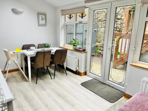 a dining room with a table and chairs and windows at Cosy Heather Cottage in Ashbourne