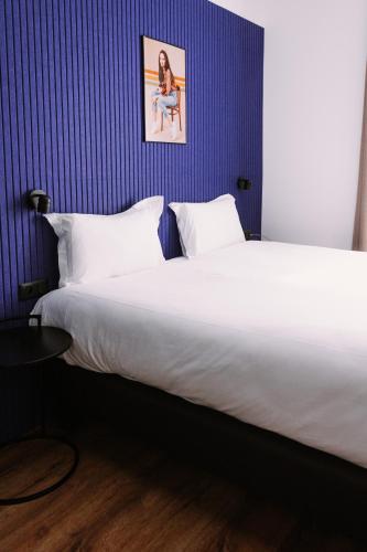 a large bed in a room with a blue wall at ClapClap Hôtel, Food & Bar in Strasbourg