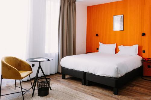 a hotel room with a bed and a chair at ClapClap Hôtel, Food & Bar in Strasbourg