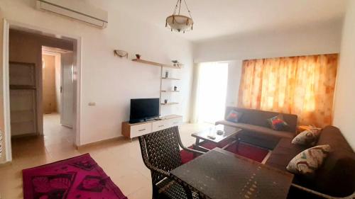 een woonkamer met een bank en een televisie bij Amwaj Oyoun hotel Nabq Bay in Sharm El Sheikh