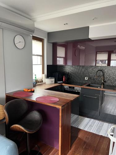 a kitchen with purple cabinets and a wooden counter top at Urus Home Sopot in Sopot