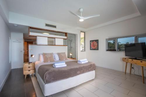 a bedroom with a bed and a flat screen tv at 1 Bright Point Apartment 5404 in Nelly Bay