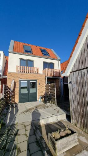 a house with a green door and a patio at Ut Endt Vlieland in Oost-Vlieland