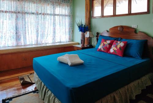 a bedroom with a blue bed with a blue sheets and windows at Casa Nena Hotel & Resort Iloilo by RedDoorz in Iloilo City