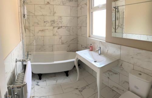 a white bathroom with a tub and a sink at Beautiful Victorian Townhouse in Liverpool