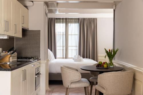アムステルダムにあるアムステルダム カナル スイーツのベッド、テーブル、椅子が備わる客室です。