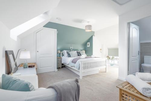 a bedroom with a white bed and a blue wall at Stoney Creek Cottage - Cosy Cottage in the heart of Crail in Crail