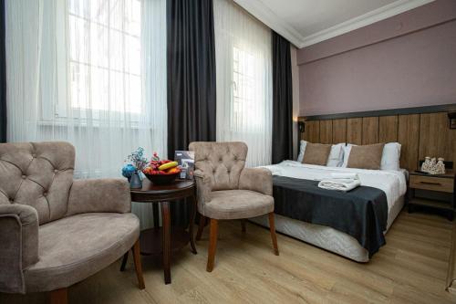 een slaapkamer met een bed en 2 stoelen en een tafel bij Comfort Hotel Taksim in Istanbul