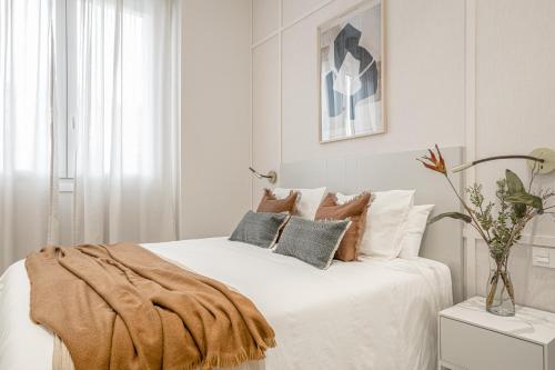 biała sypialnia z białym łóżkiem z poduszkami w obiekcie Apartamentos Pamplona by Clabao w Pampelunie