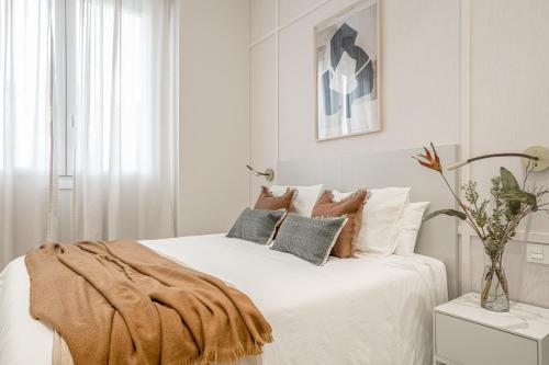 - une chambre blanche avec un lit blanc et des oreillers dans l'établissement Apartamentos Pamplona by Clabao, à Pampelune