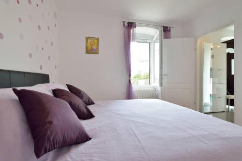 a bedroom with a large white bed with purple pillows at Apartment Opatija Lavanda in Opatija