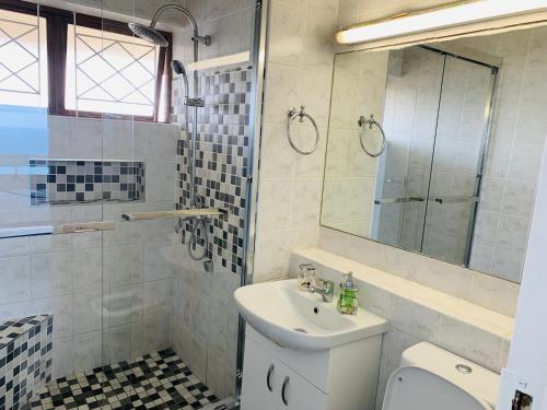 a bathroom with a sink and a toilet and a mirror at Serene Seascape Apartments in Amanzimtoti