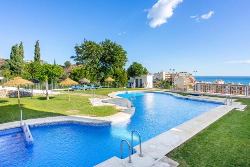a swimming pool in a resort with the ocean in the background at Loft near Carvajal beach by Costarentals - Ref 16 in Torremuelle