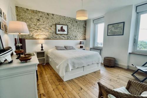 - une chambre avec un lit blanc et un mur en pierre dans l'établissement Ti-maen - La maison de pierres, à Roscanvel