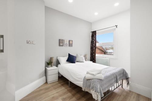 a white bedroom with a large bed and a window at 3BR Duplex Penthouse Harrow centre in Harrow